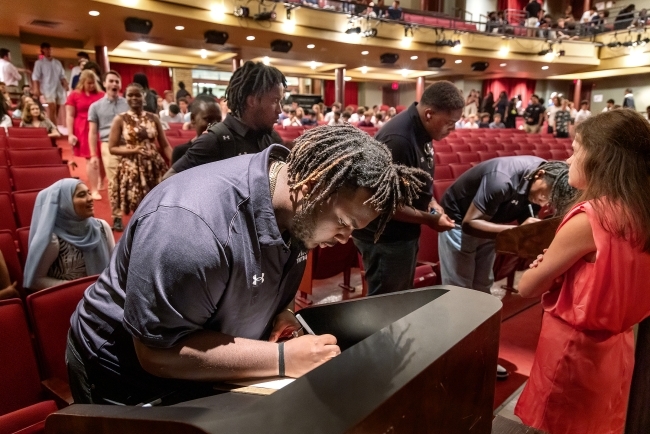 student signs Honor Code in auditorium