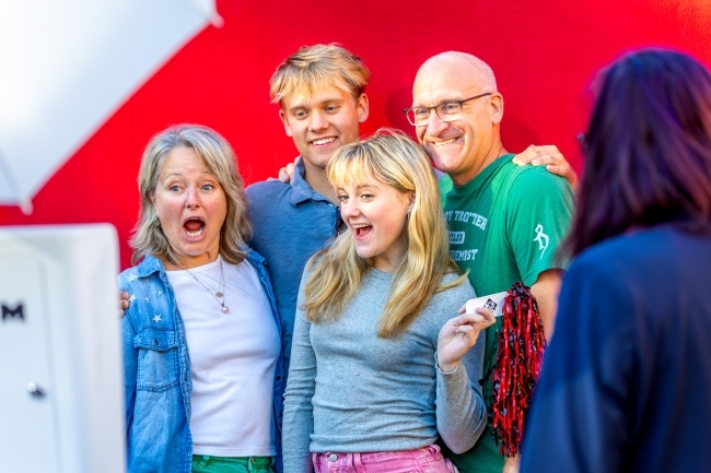 a group of students and their parents smiling in front of a photo backdrop