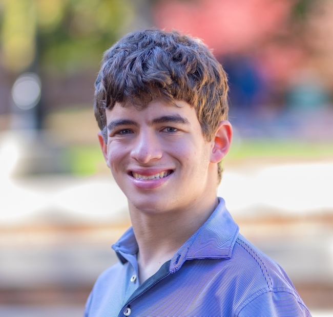 a young white man wearing a polo and smiling