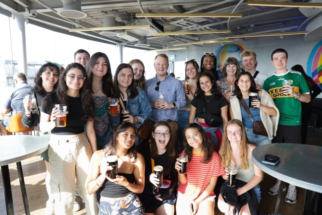 a group of students on a boat smiling and holding beverages