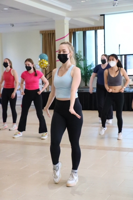 a group of young women in athletics and masks dance