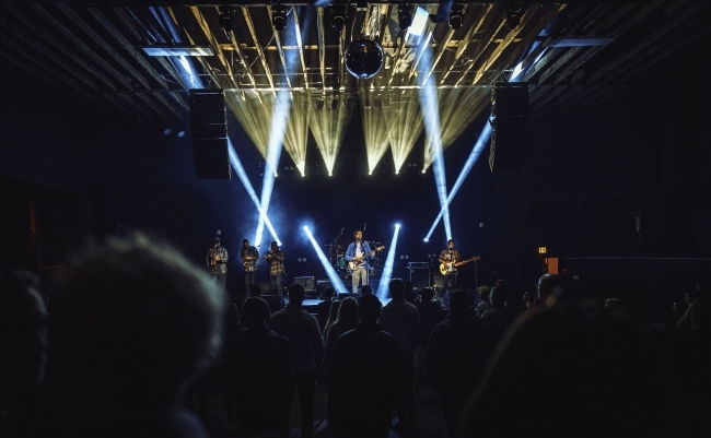 a band on stage with bright lights and a dark background