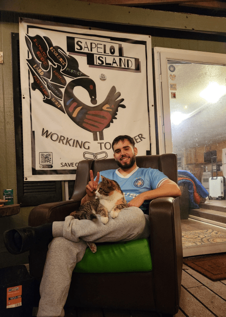 a young man sits on a porch holding a cat