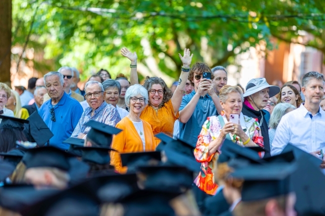 a group of families stand and wave at a graduation ceremony