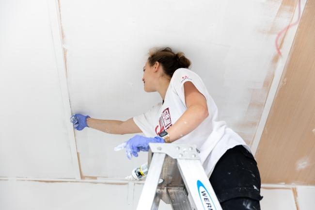 Student painting ceiling of tiny house