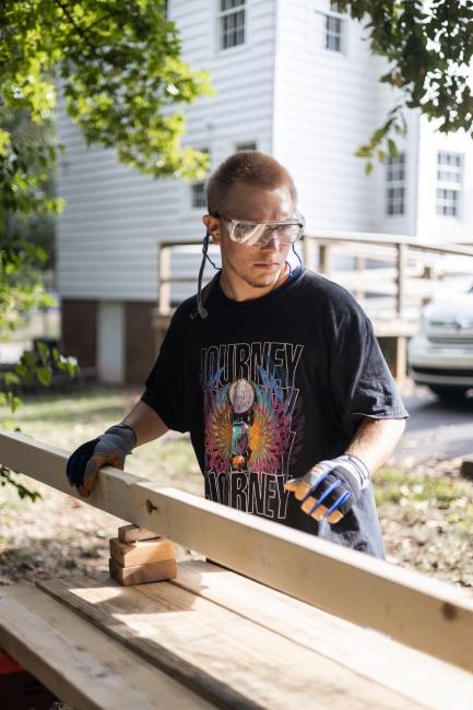 Student wearing safety glasses cutting lumber