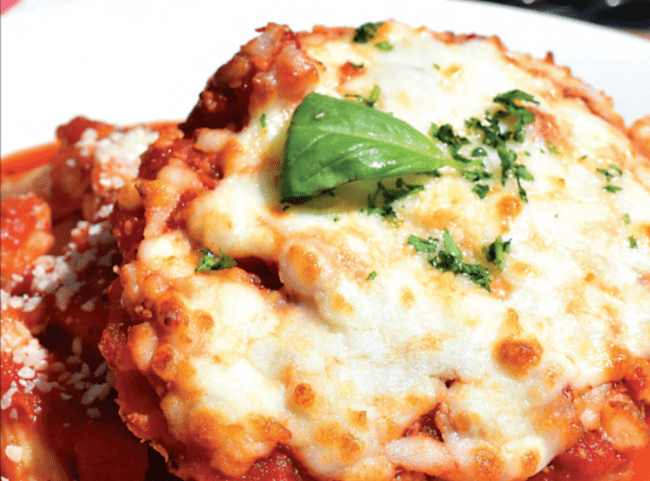 a piece of chicken parmesan covered in red sauce and basil