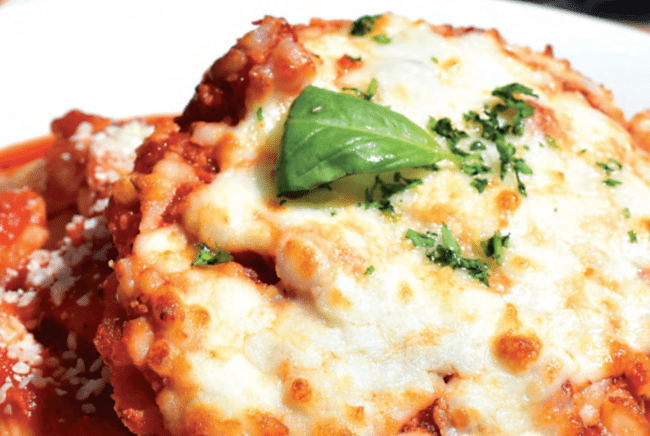 a piece of chicken parmesan covered in red sauce, cheese and basil