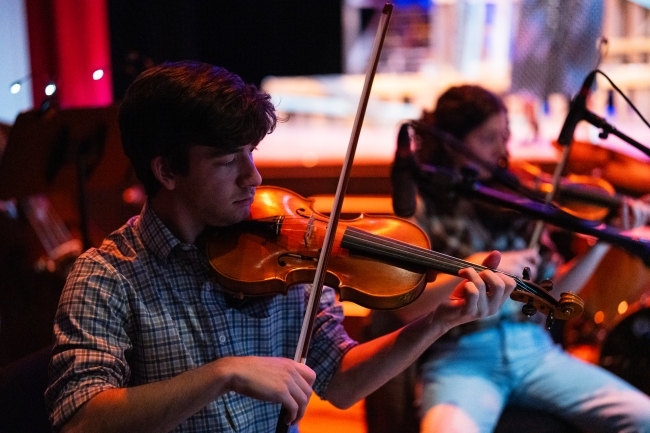 a young man plays in the Appalachian ensemble during a musical