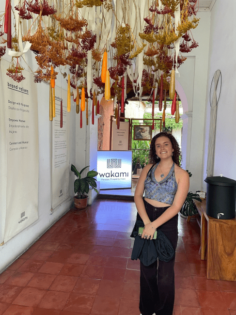 a young woman standing in a museum with art hanging from the ceiling