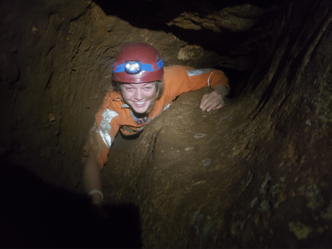a young woman climbing in a cave