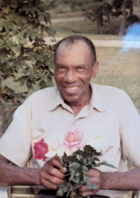 an older Black man holding a rose bush