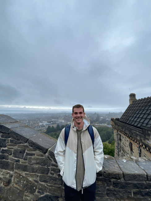 a young white man standing on top of an old stone building