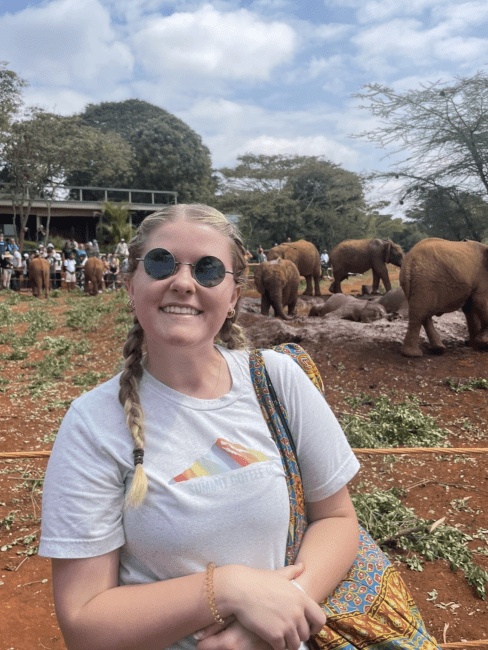 a young white woman wearing a tshirt and sunlgasses outside