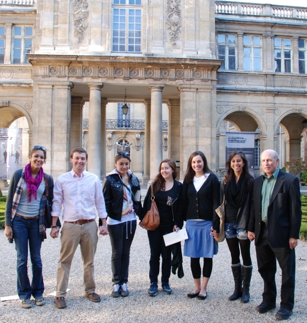 a group of students and their professor stand in front of an old building in France