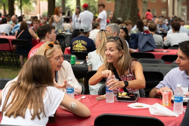 Friends chat at a table at the orientation picnic