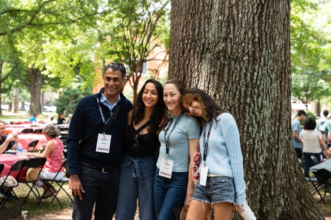 A group of people smile at the orientation picnic in front of a tree