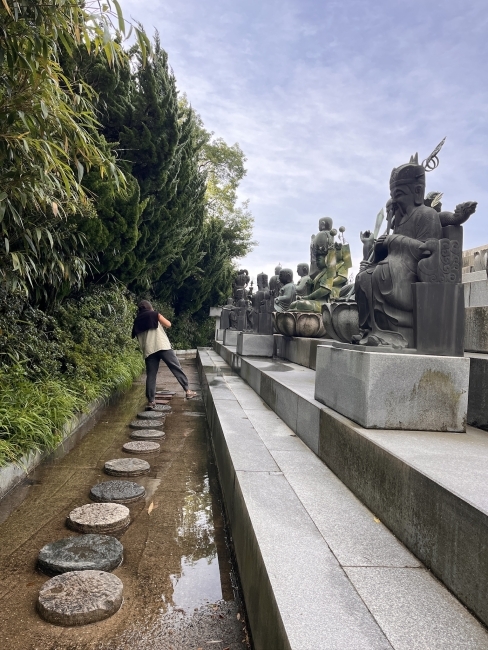 a young woman walks along a stone path at a Buddhist temple