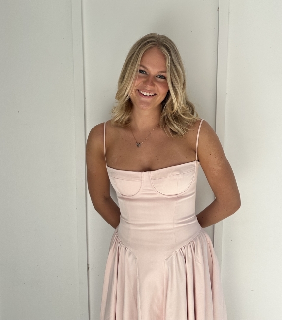 a young white woman leaning against a white wall