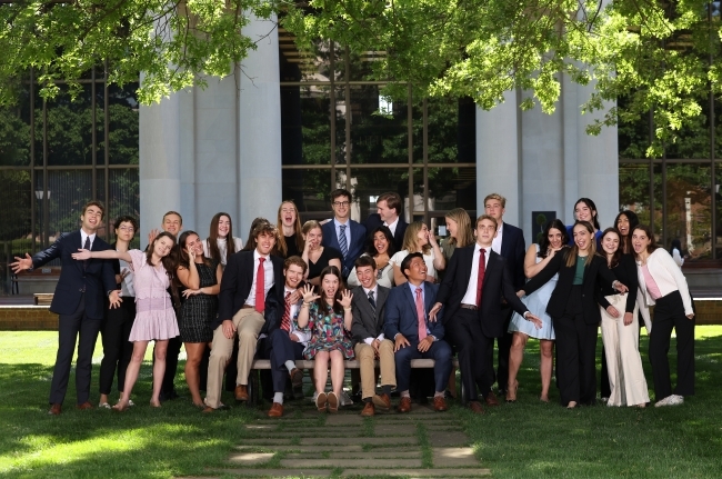 a large group of students in business formal making silly faces and smiling