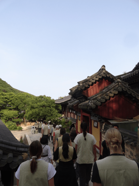 a group of students walking in front of a Buddhist temple in Korea