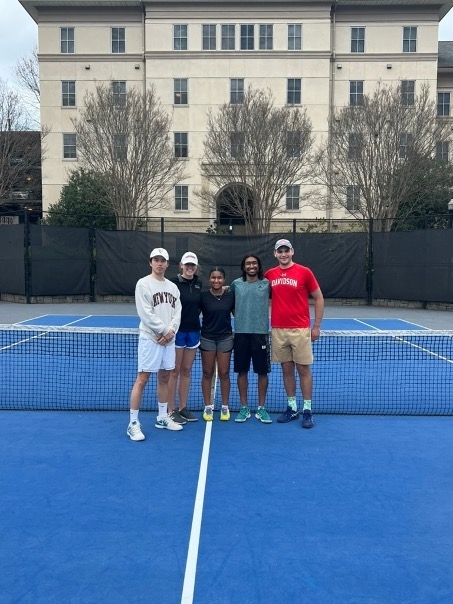 a group of five young students standing on a tennis court