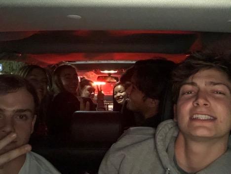 a group of students take a selfie in a car at night