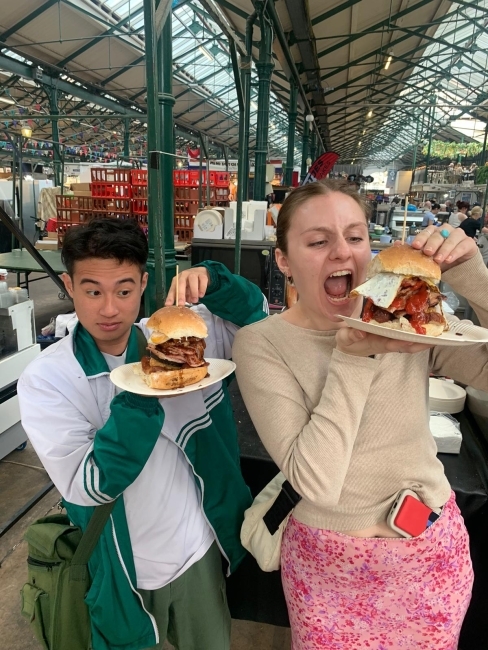 a young man and woman eat sandwiches at a market