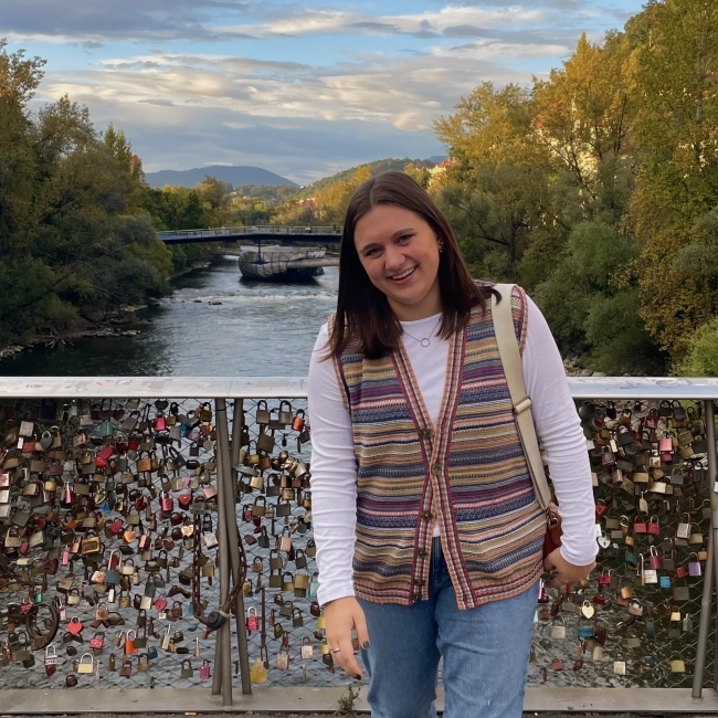 a young white woman standing on a bridge covered with locks