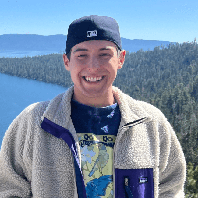 a young white male wearing a backwards cap overlooking a lake