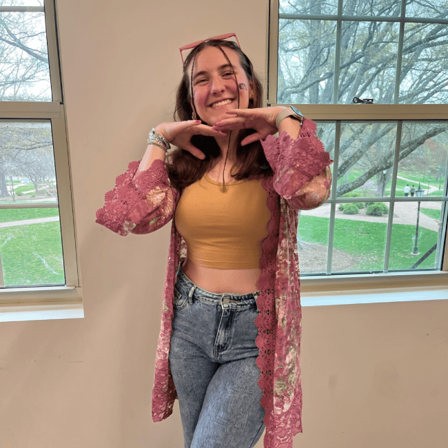 a young white woman smiling in front of windows