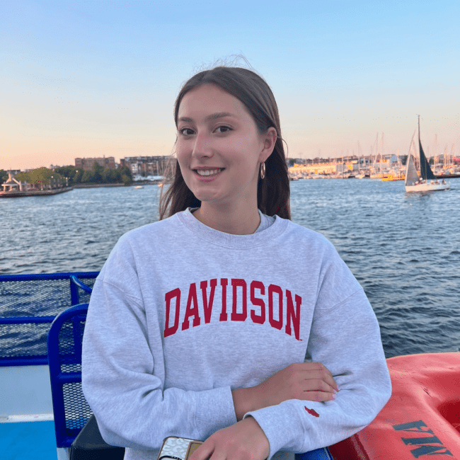 a young white woman wearing a Davidson sweatshirt overlooking a harbor