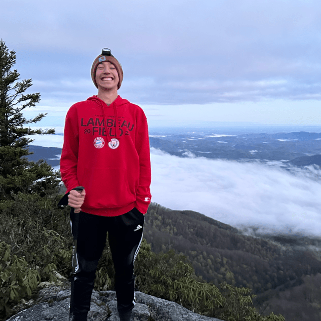 a young white man standing on a mountain top