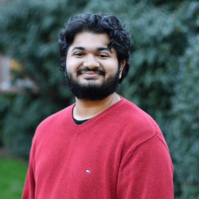 a young man wearing a red sweater and smiling