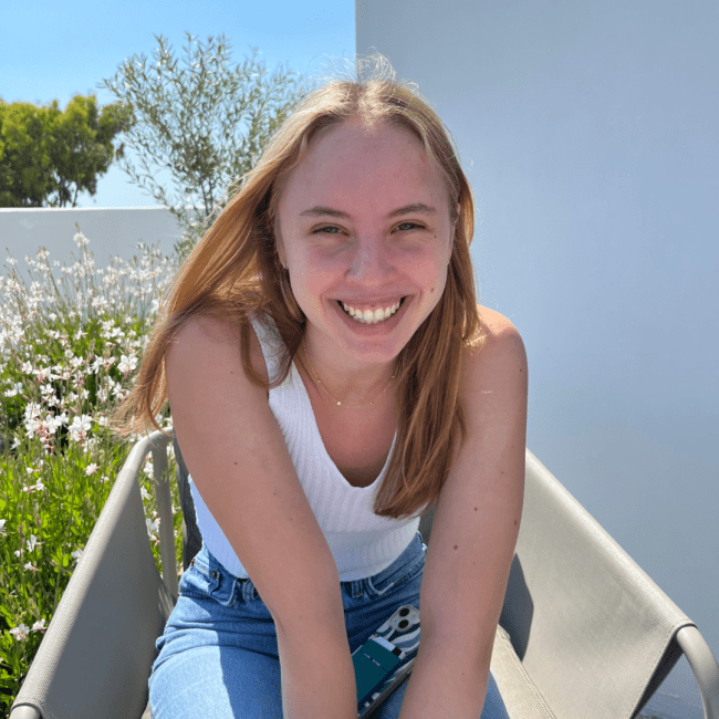 a young white woman smiling in front of a field of flowers