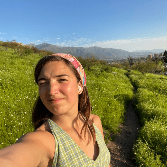 a young woman wearing a bandana and standing in front of a grassy field