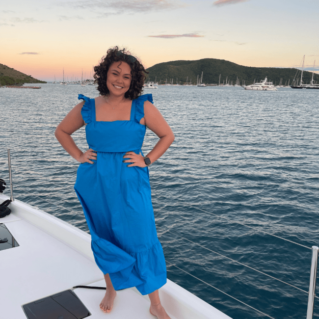 a young woman wearing a blue sundress standing on a boat