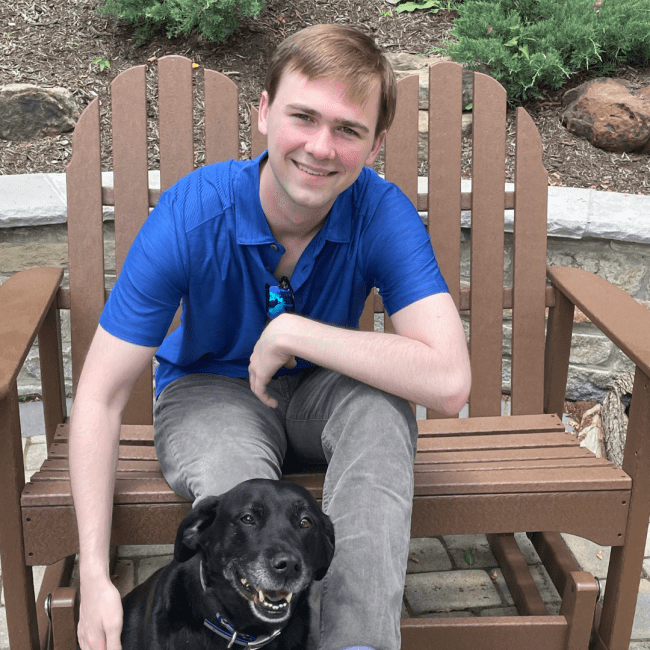 a young white man sitting in a chair with a black dog