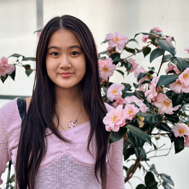 a young Asian woman smiling in front of a floral arrangement