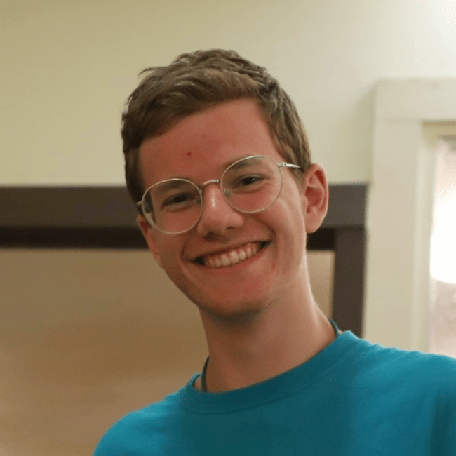 a young white man smiling wearing glasses