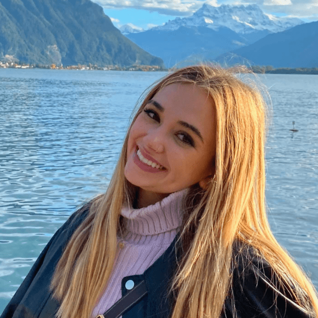 a young white woman standing in front of a lake