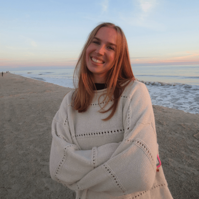 a young white woman smiling on a beach at sunset