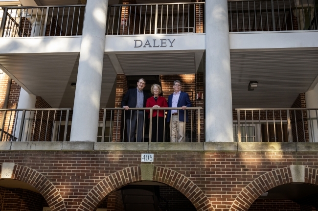 three older people standing together on a balcony that reads "Daley"