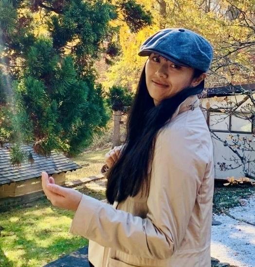 a young Asian woman outside with a jacket and hat on