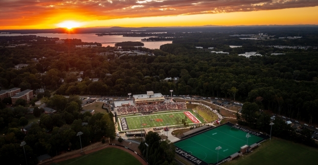 an aerial view of a college campus and lake at sunset