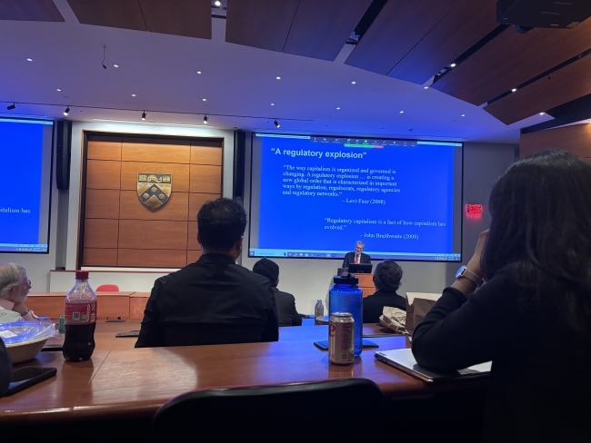 a man speaks at a podium in a modern lecture hall