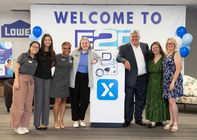 a group of people standing together in front of an E2D wall