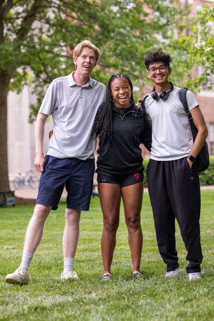 a group of three students stand together smiling