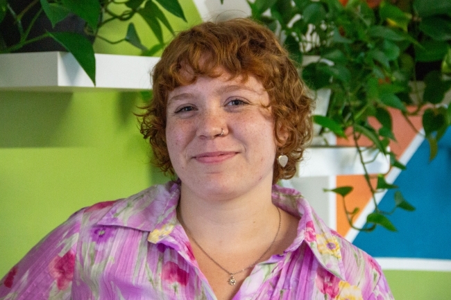 a young white woman with red hair wearing a pink top and smiling