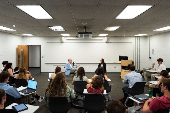 an older man talks to a classroom of students